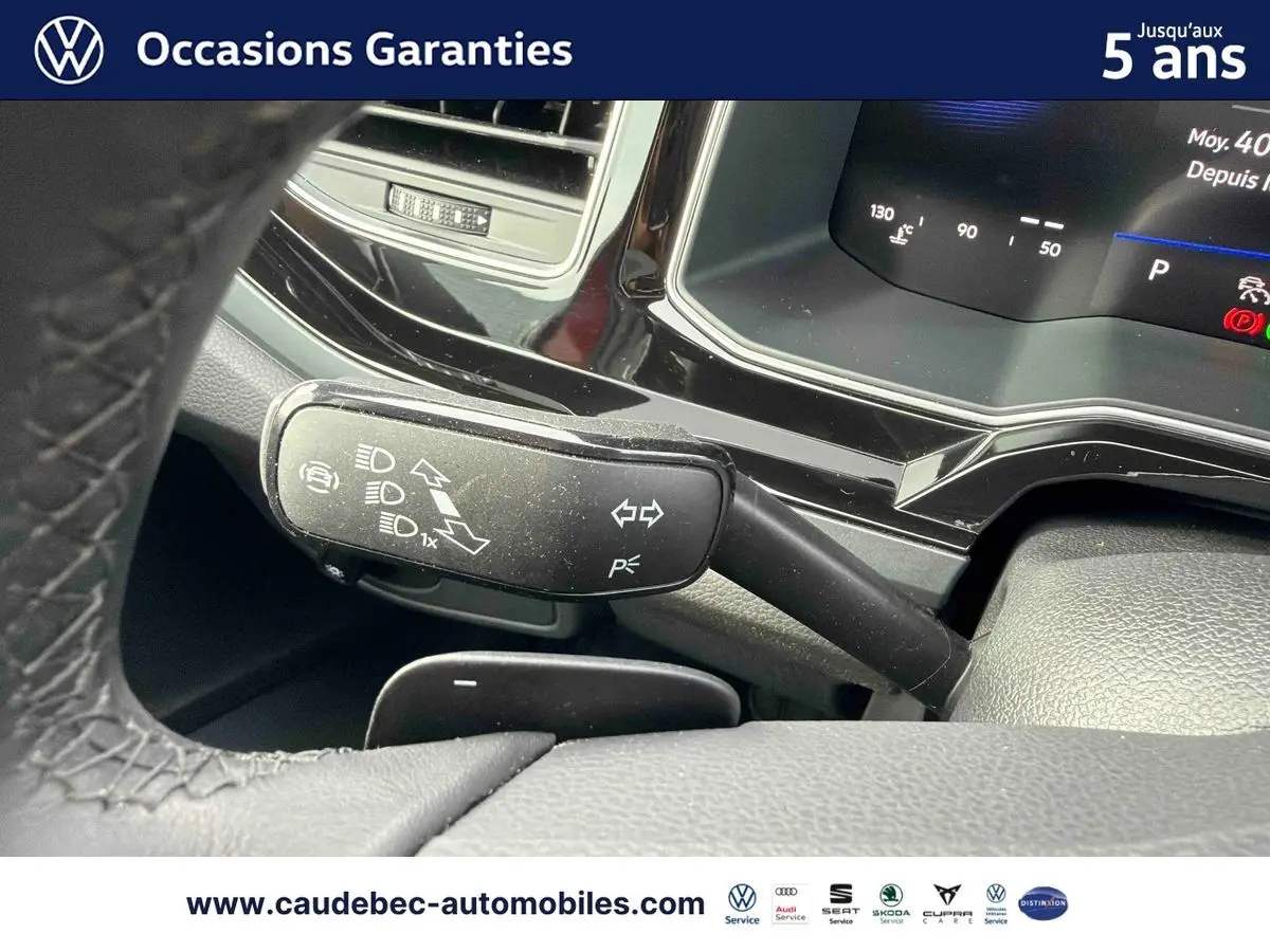 Gros plan sur la commande des clignotants et feux dans l’habitacle d’une Volkswagen Polo rouge, tableau de bord digital visible.