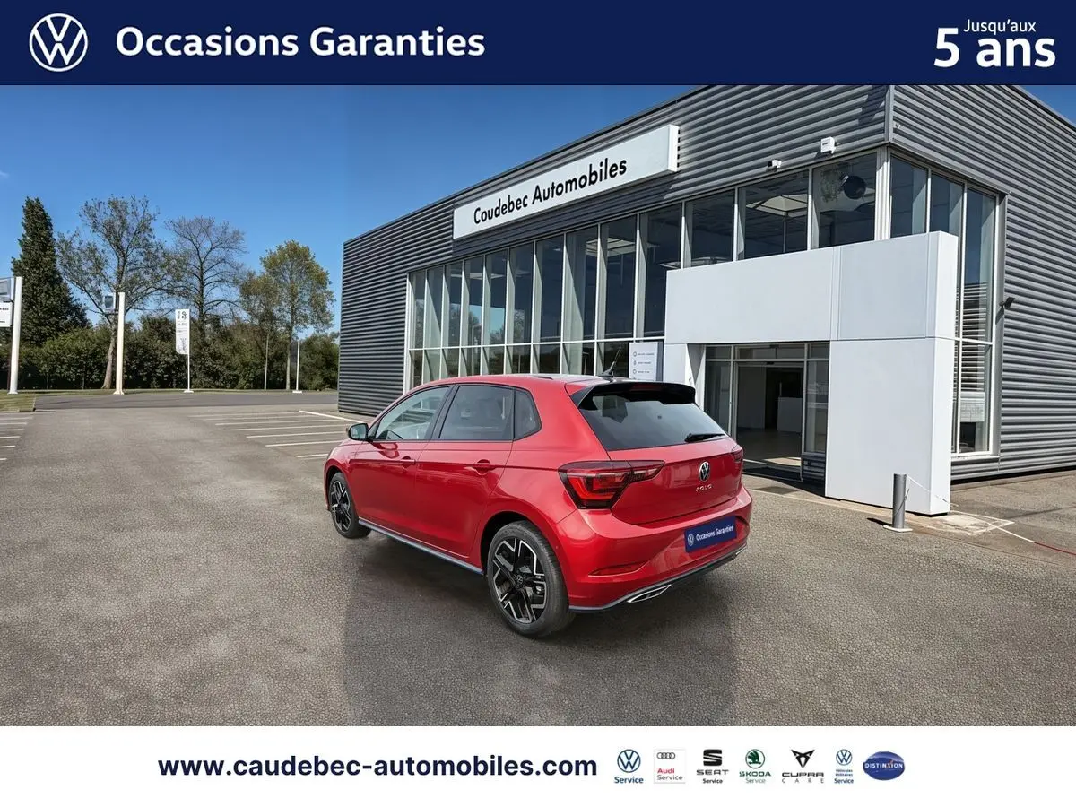 Volkswagen Polo rouge vue 3/4 arrière droit, avec jantes alliage 17 pouces, stationnée devant un bâtiment moderne.