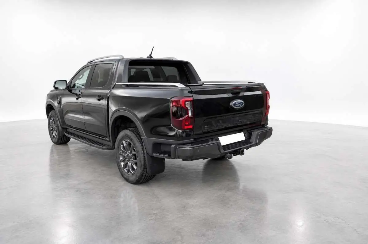 Ford Ranger 2.0 Wildtrak Plus noir agate vu 3/4 arrière droit avec arceau sport et barres de toit visibles.