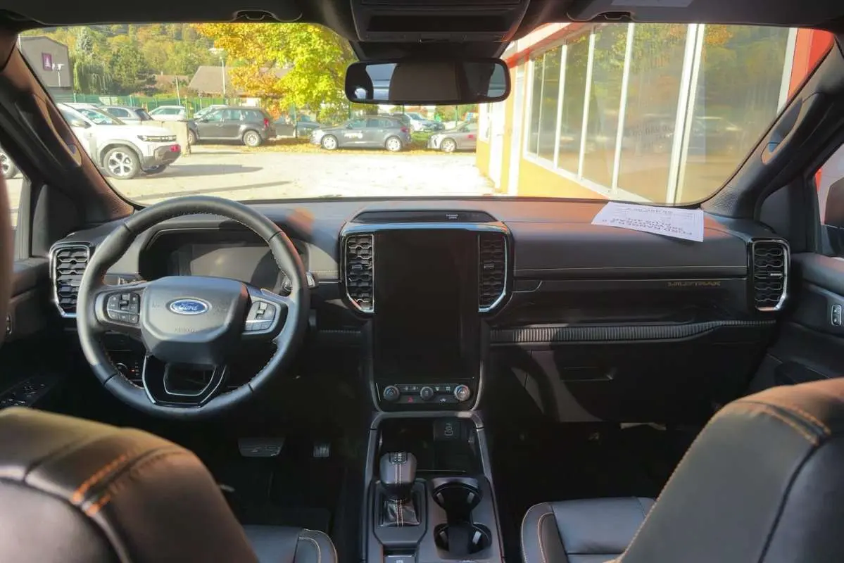 Vue intérieure avant du Ford Ranger Wildtrak 2026 avec tableau de bord noir, grand écran vertical et volant cuir multifonctions.