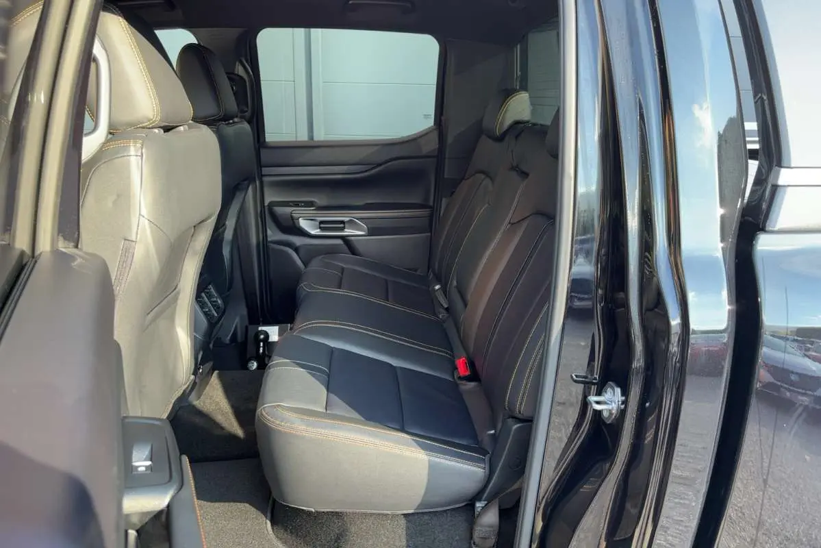 Vue latérale intérieure du Ford Ranger 2026 noir agate, montrant les sièges arrière en cuir avec surpiqûres contrastées.