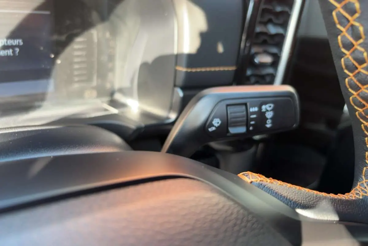Détail intérieur du Ford Ranger Wildtrak 2026 montrant le volant cuir noir avec surpiqûres orange et commande des essuie-glaces.