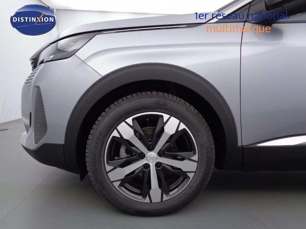 Gros plan sur la roue avant gauche et l'aile d'un Peugeot 3008 gris Artense métal, finition Allure Pack 2023.