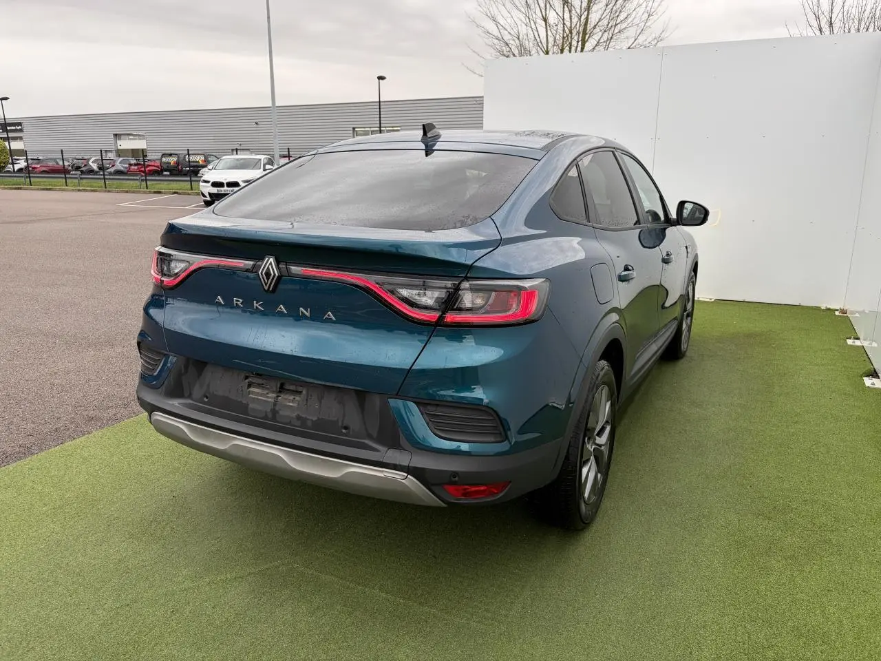 Vue 3/4 arrière droite d'un Renault Arkana bleu Zanzibar métallisé avec feux arrière LED et vitres surteintées.