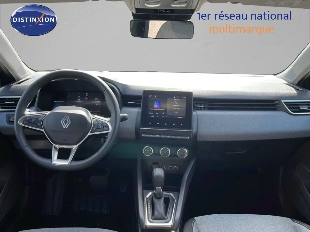 Vue intérieure avant de la Renault Clio 2025, tableau de bord gris avec écran tactile et volant multifonction.