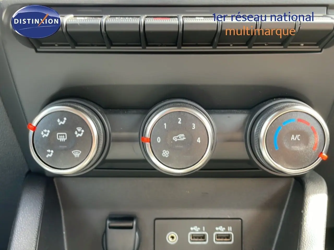 Gros plan sur les commandes de climatisation et les ports USB de la Renault Clio gris schiste, intérieur noir.