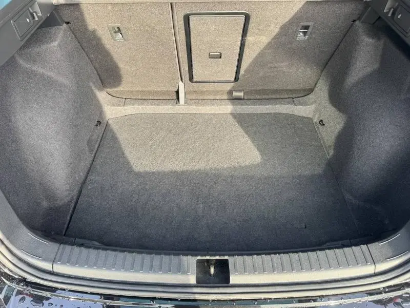 Coffre vide vu de dessus du SEAT Ateca 2024 noir, avec banquette arrière rabattable et tapis gris.