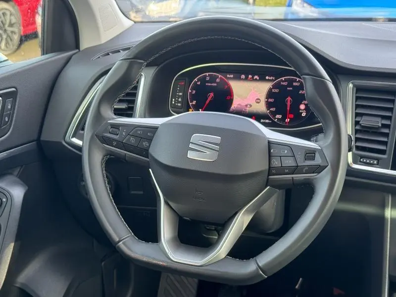 Vue rapprochée du volant cuir multifonction et du tableau de bord numérique du SEAT Ateca noir, affichant la navigation.