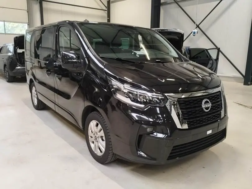 Nissan Primastar noir vue 3/4 avant droit, avec calandre chromée et phares LED dans un garage.