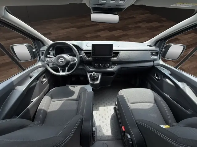 Vue intérieure avant du Nissan Primastar 2025 noir, tableau de bord moderne avec écran tactile central et volant multifonctions.