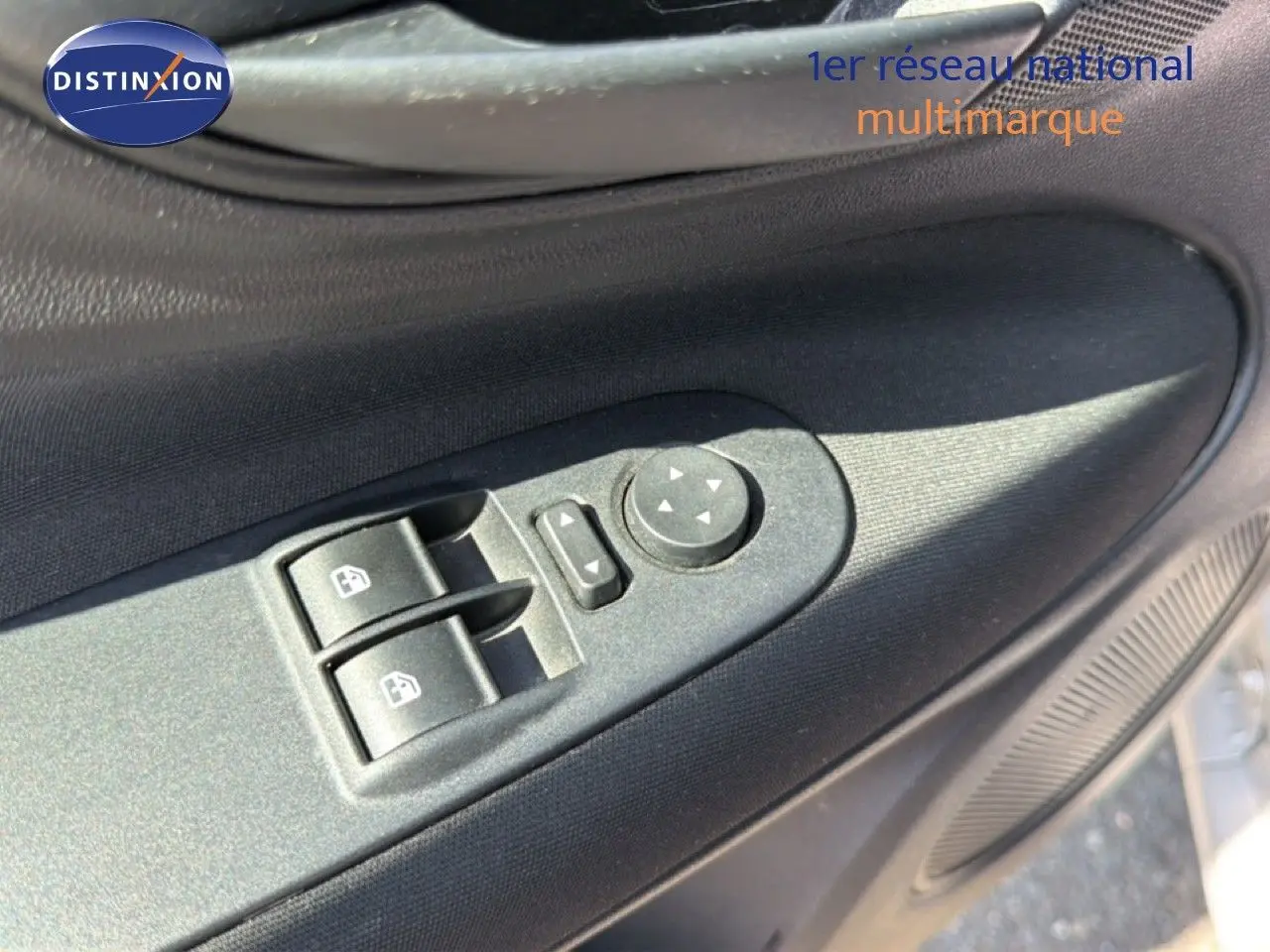 Gros plan sur les commandes électriques des vitres et rétroviseurs côté conducteur d'une Fiat Punto gris argent 2016.