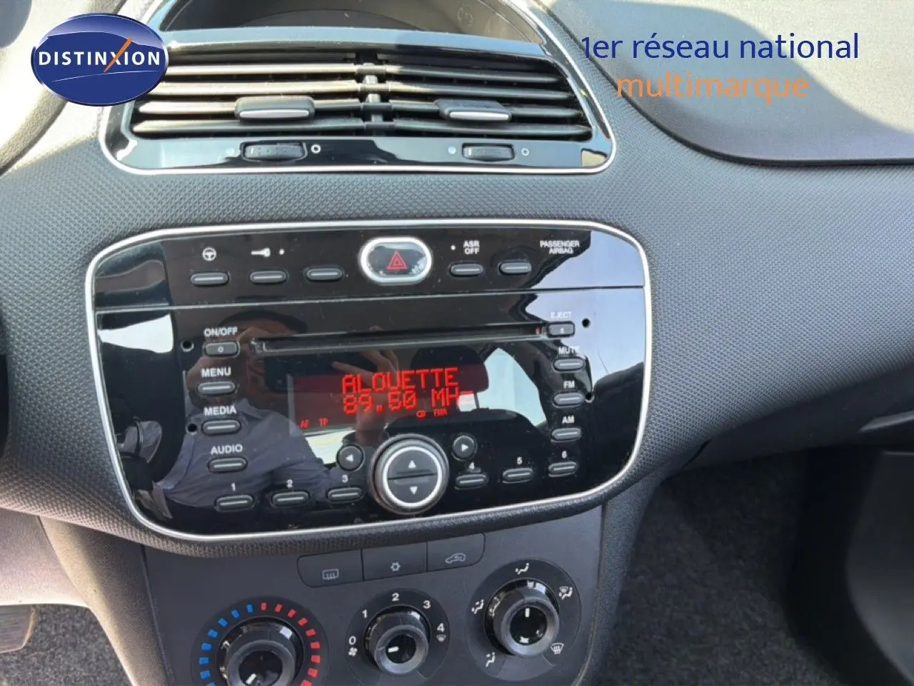 Vue rapprochée du tableau de bord noir et gris argent de la Fiat Punto Street 2016 avec radio affichant la fréquence FM.