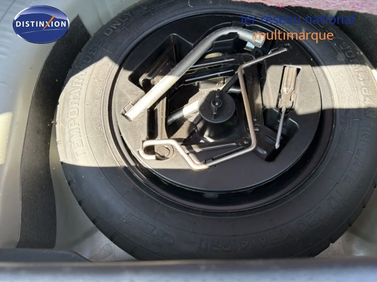 Roue de secours avec outils de changement logée dans le coffre d'une Fiat Punto Street gris argent 2016.