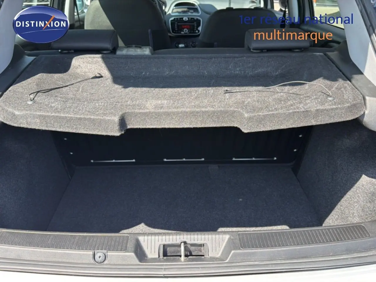 Vue intérieure du coffre ouvert d'une Fiat Punto Street gris argent de 2016, montrant la plage arrière et l'habitacle.