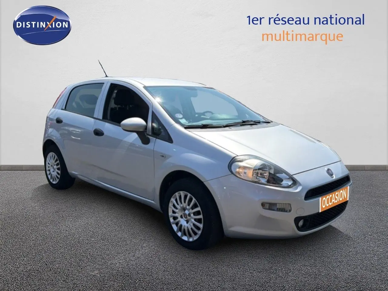 Fiat Punto Street gris argent vue 3/4 avant droit, compacte 5 portes avec jantes alliage et phares allumés.