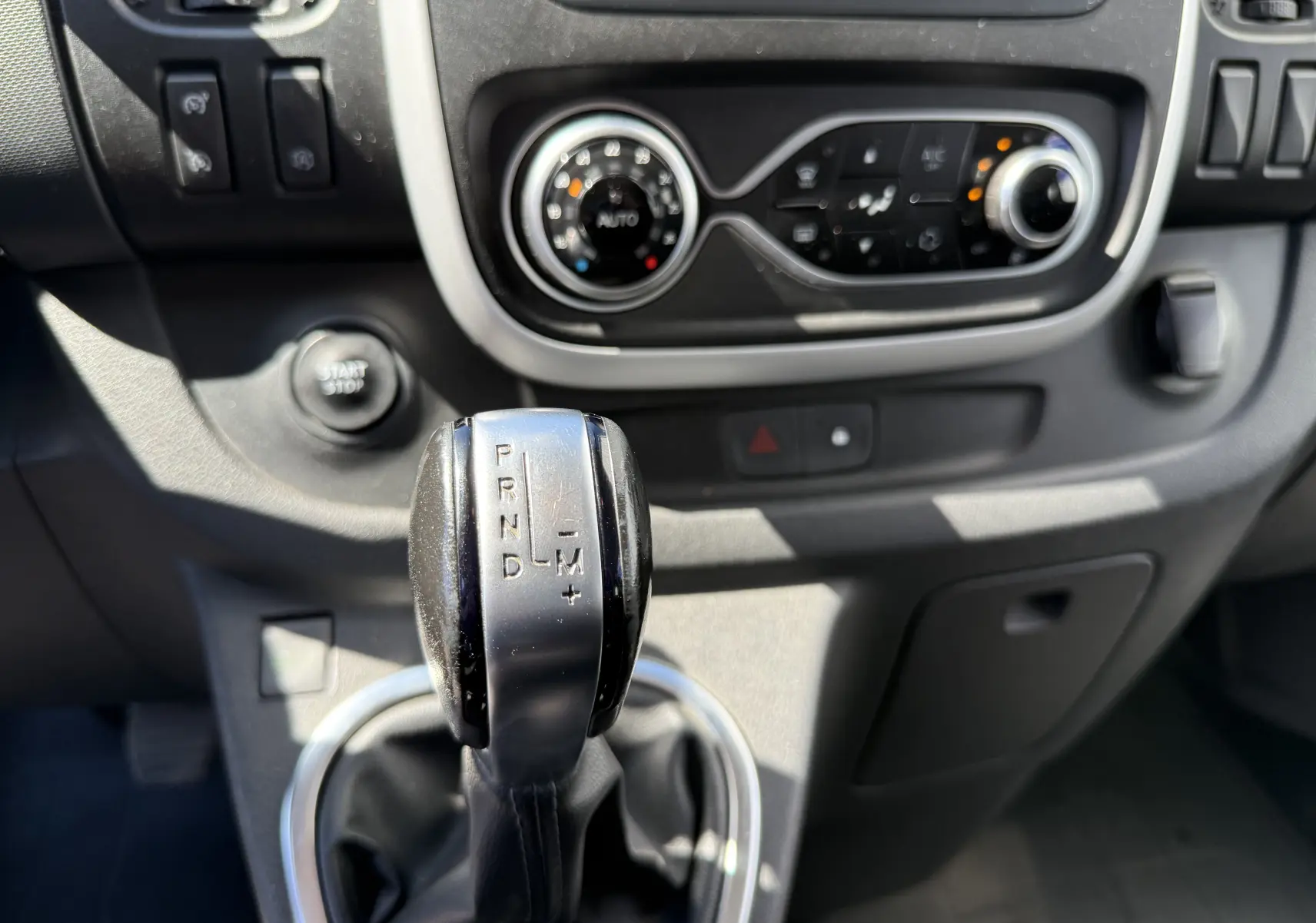 Gros plan sur le levier de vitesse automatique et la console centrale du Renault Trafic gris, vue intérieure avant.