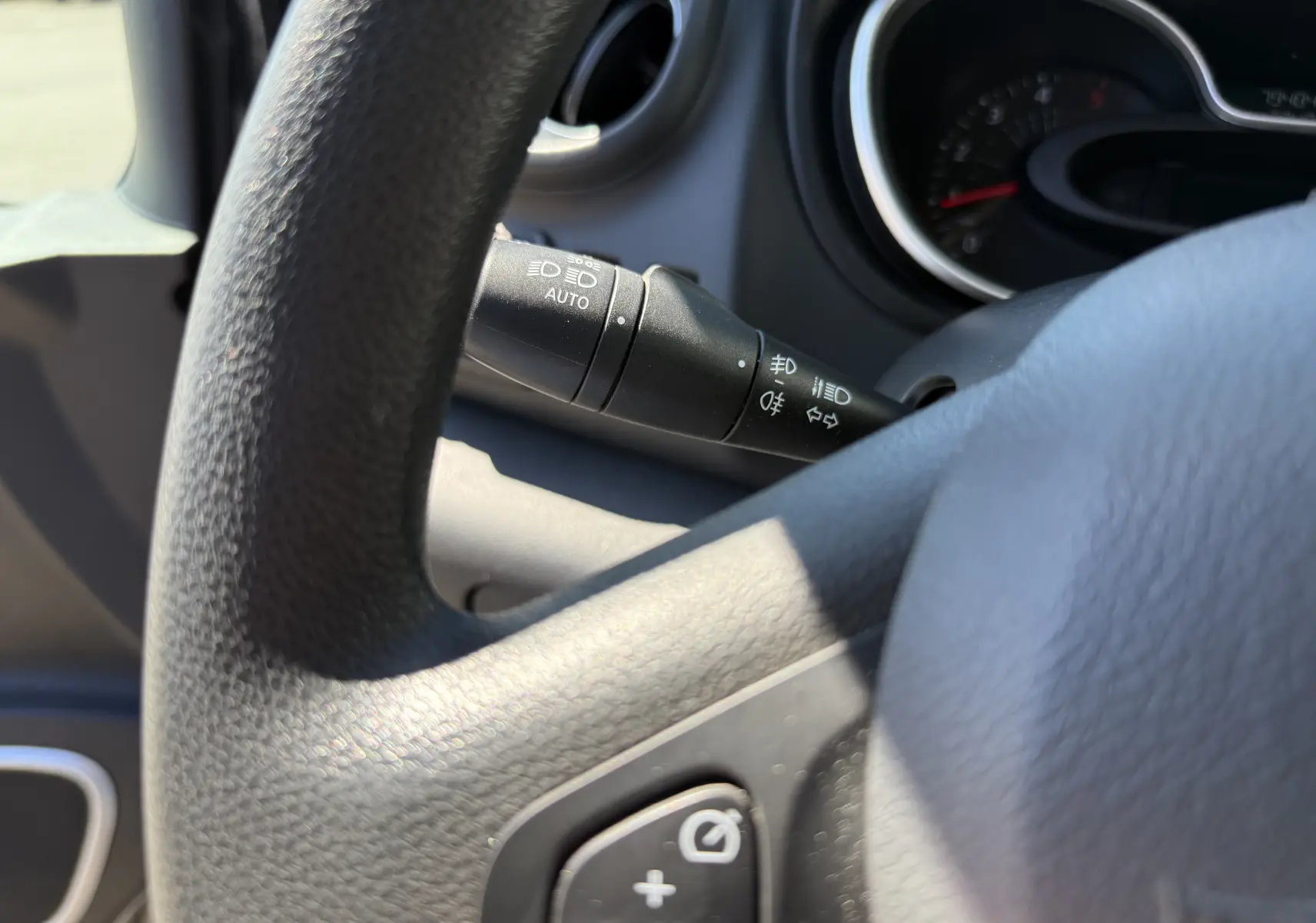 Gros plan sur le commodo d’éclairage à gauche du volant du Renault Trafic gris, avec tableau de bord en arrière-plan.