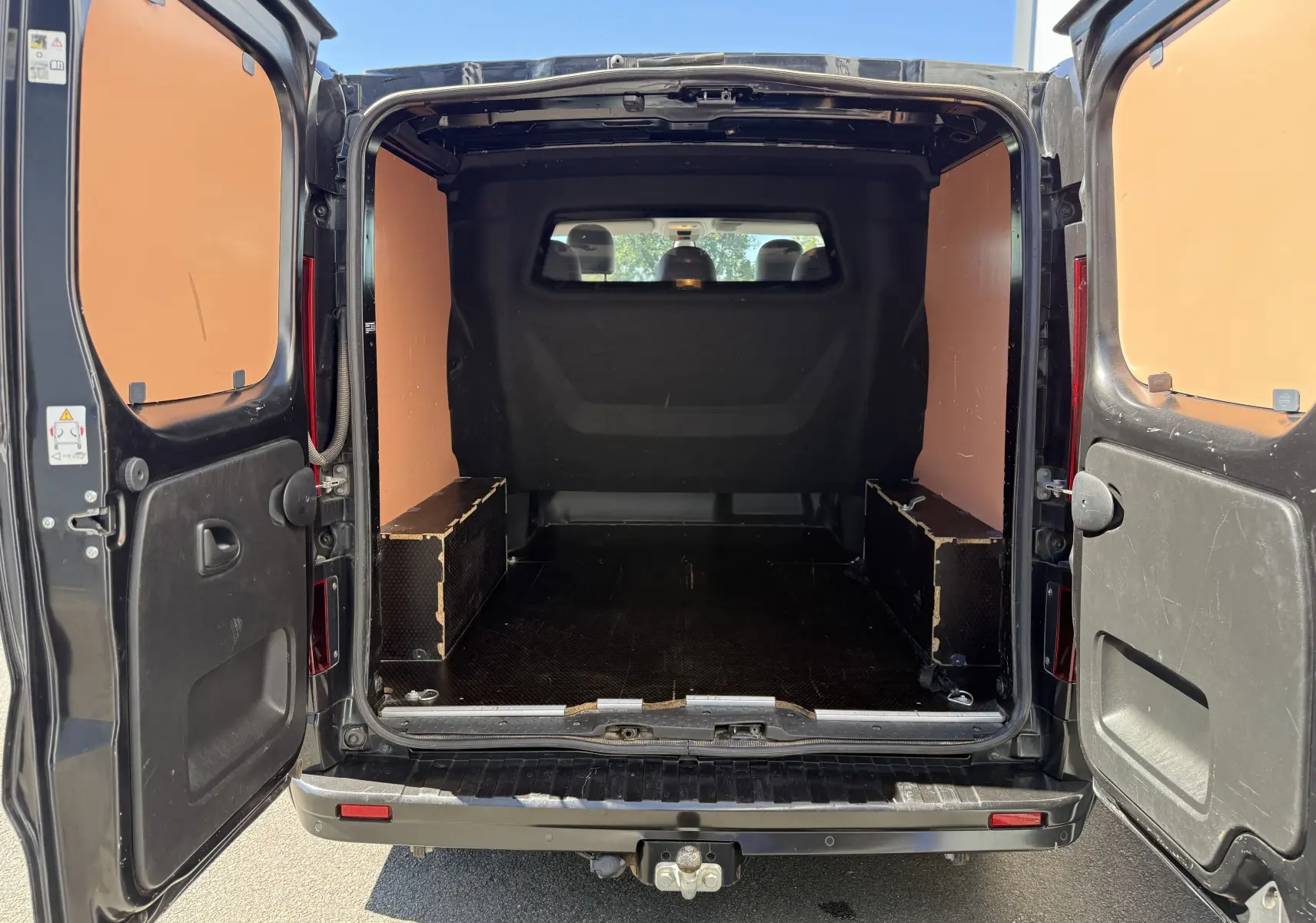Vue arrière ouverte du Renault Trafic cabine approfondie gris 2021, montrant l’espace de chargement avec panneaux bois latéraux.