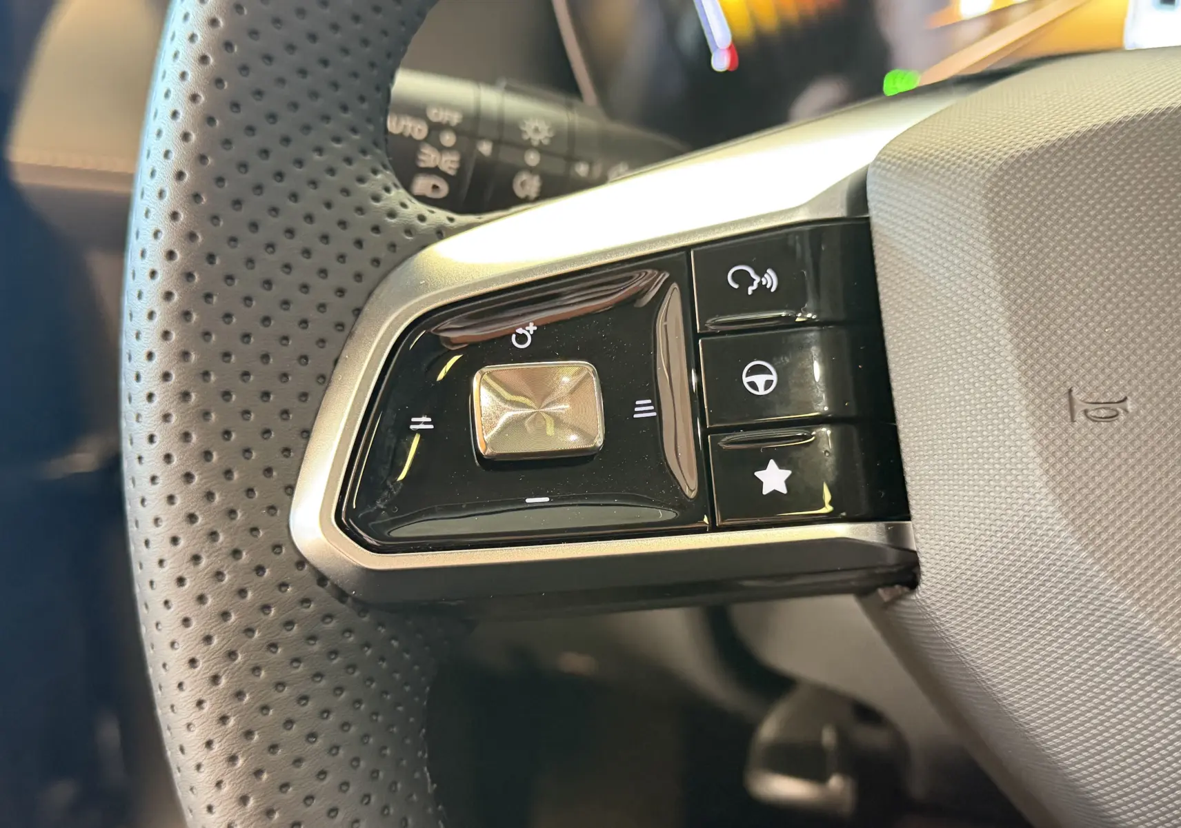 Gros plan sur les commandes gauche du volant en cuir perforé du MG ZS 2026 Candem Grey, boutons multifonctions.