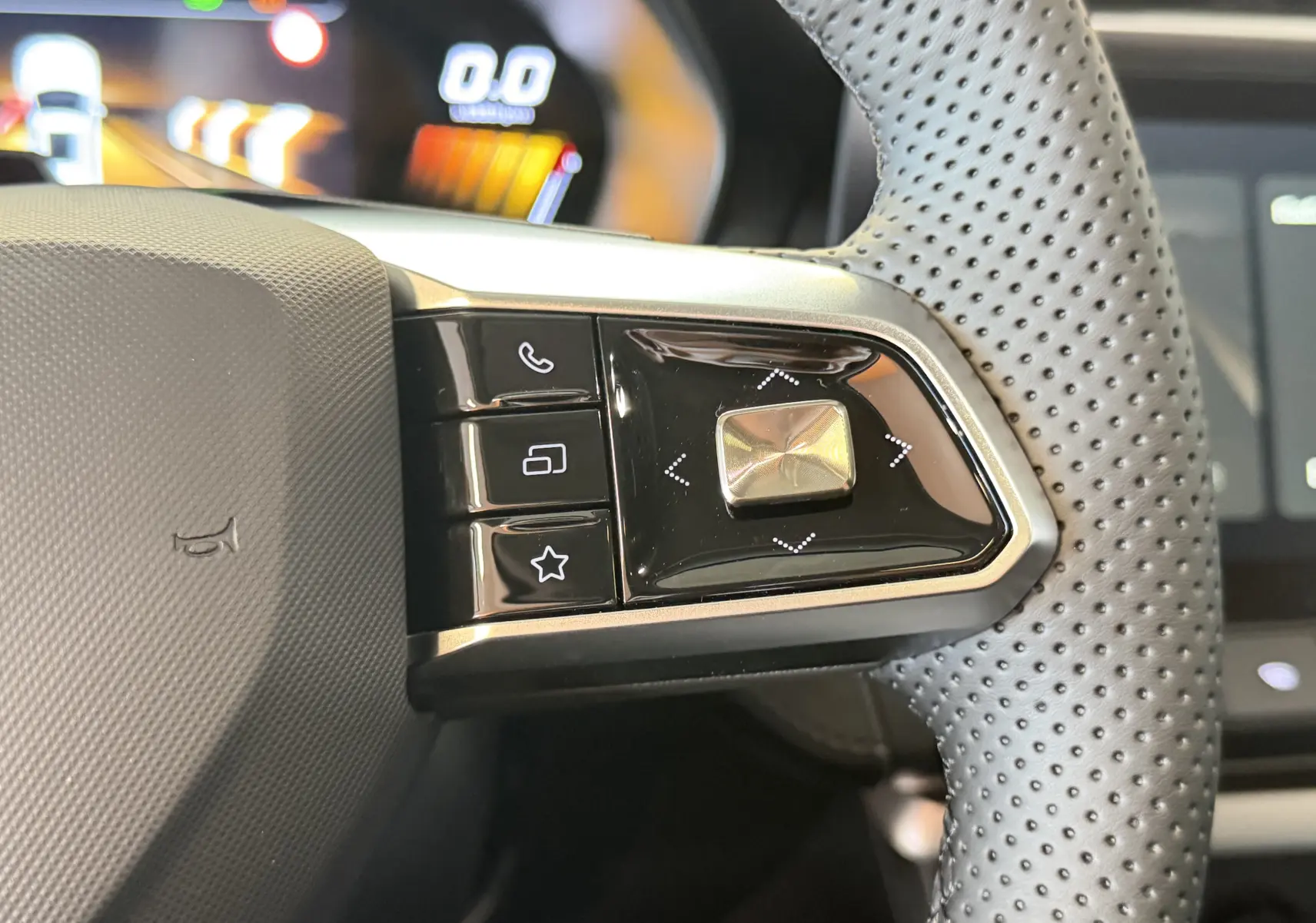 Gros plan sur les commandes à droite du volant perforé noir du MG ZS 1.5 L Hybrid+ 2026 avec affichage numérique en arrière-plan.
