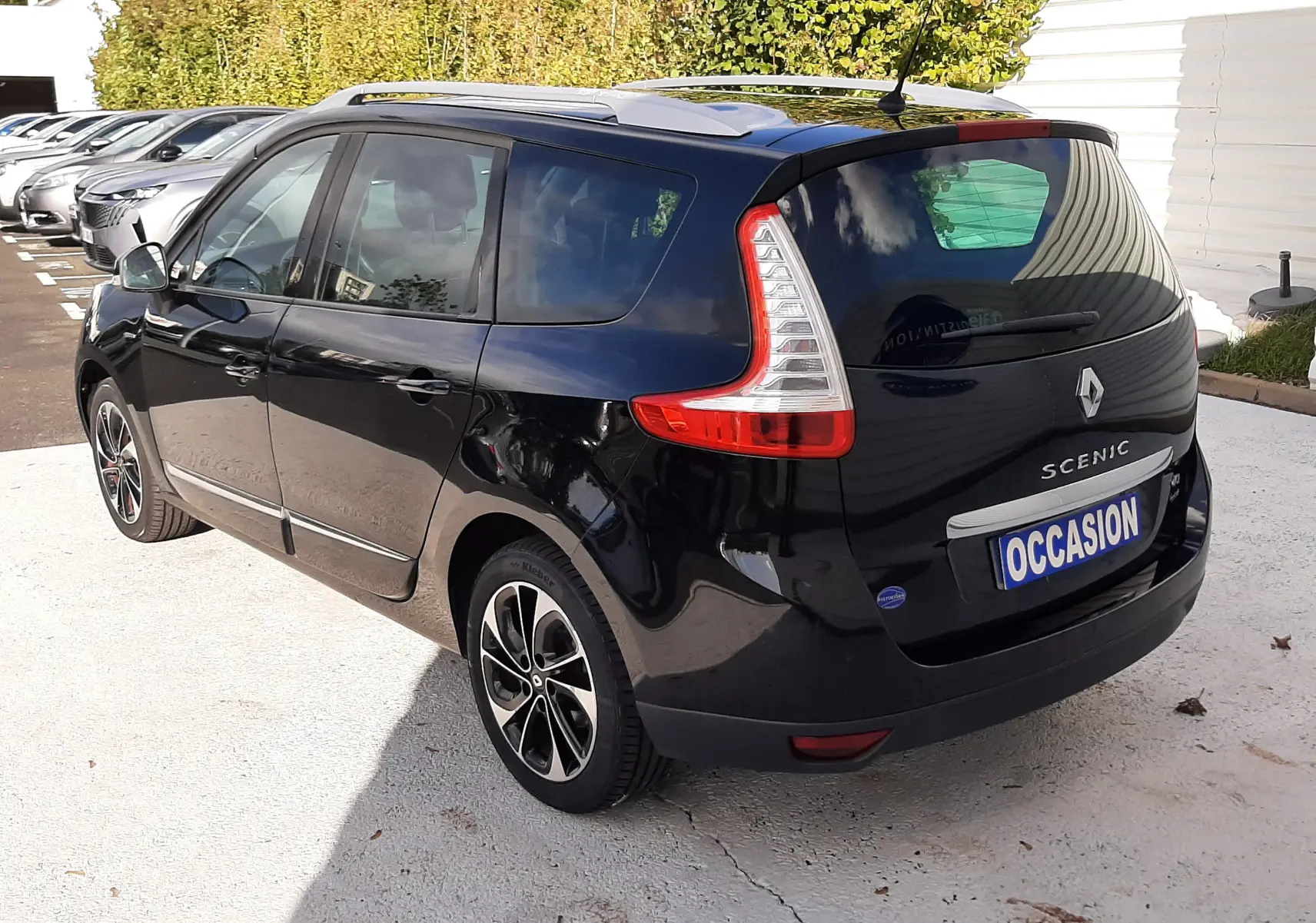 Renault Grand Scénic noir en 3/4 arrière droit, avec feux arrière caractéristiques et jantes alliage bicolores.