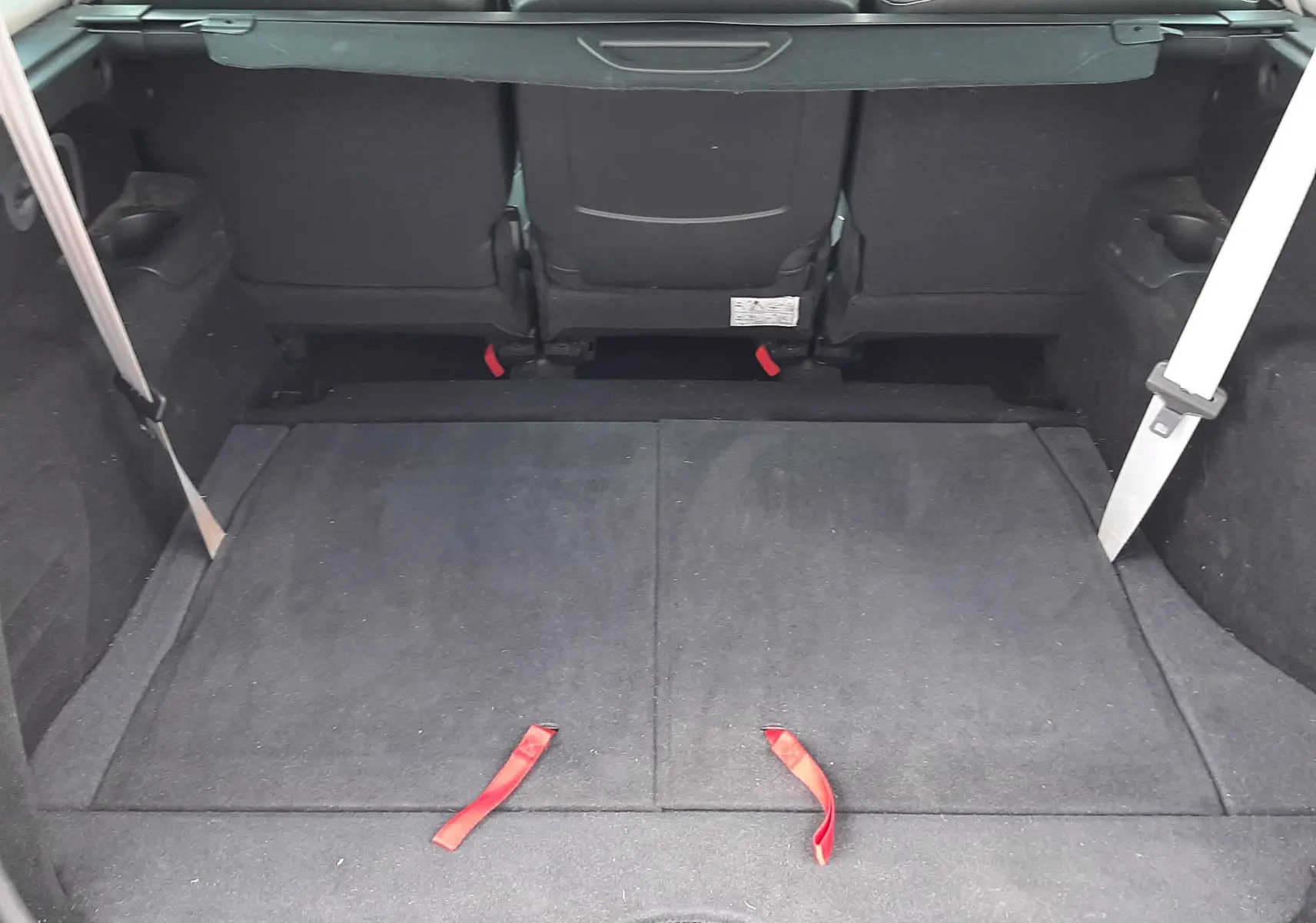Coffre ouvert vu de l'arrière d'un Renault Grand Scenic noir, montrant la banquette arrière et l'espace de chargement.