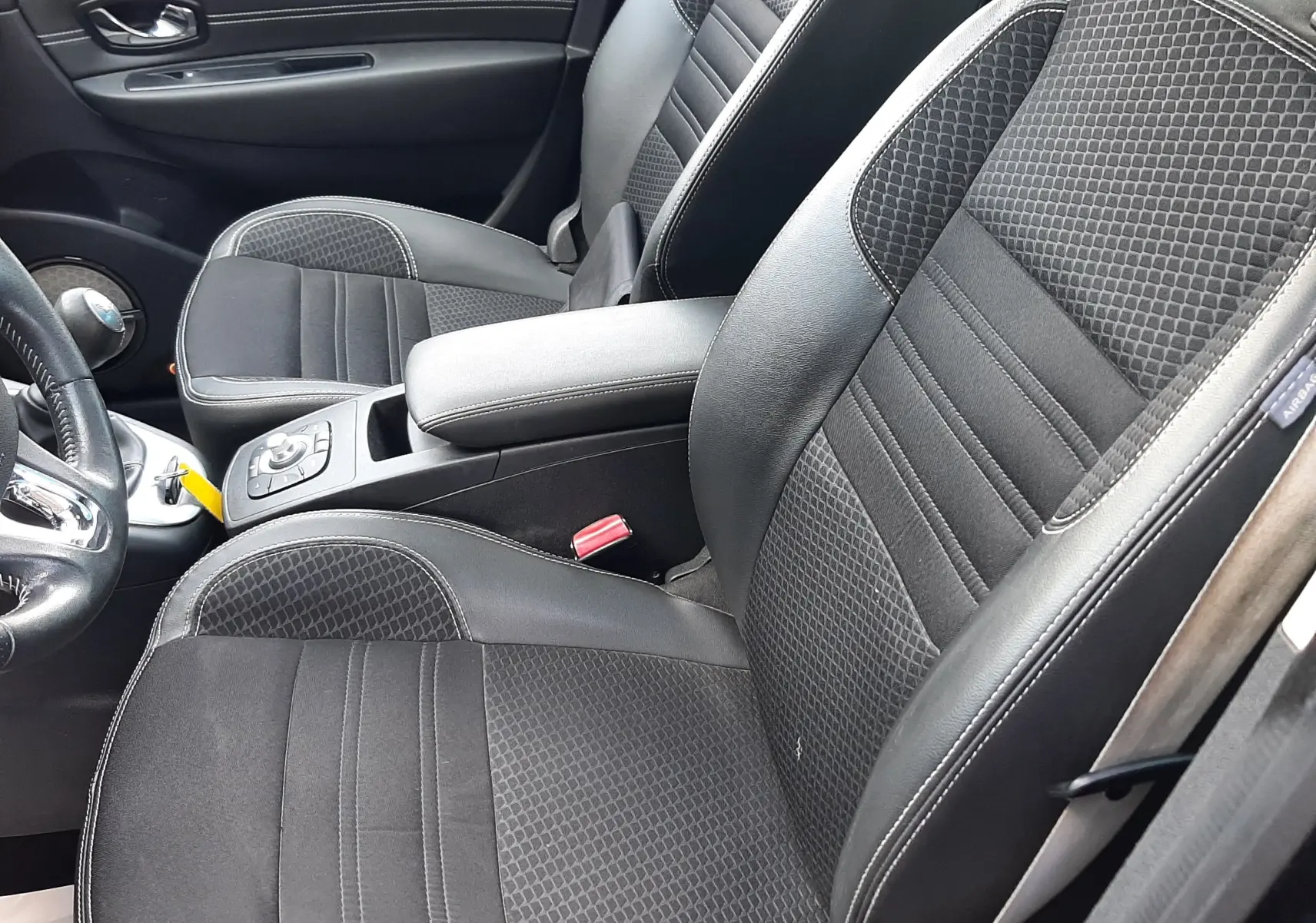 Vue intérieure côté droit du Renault Grand Scenic noir 2015, sièges avant en cuir et tissu avec accoudoir central.