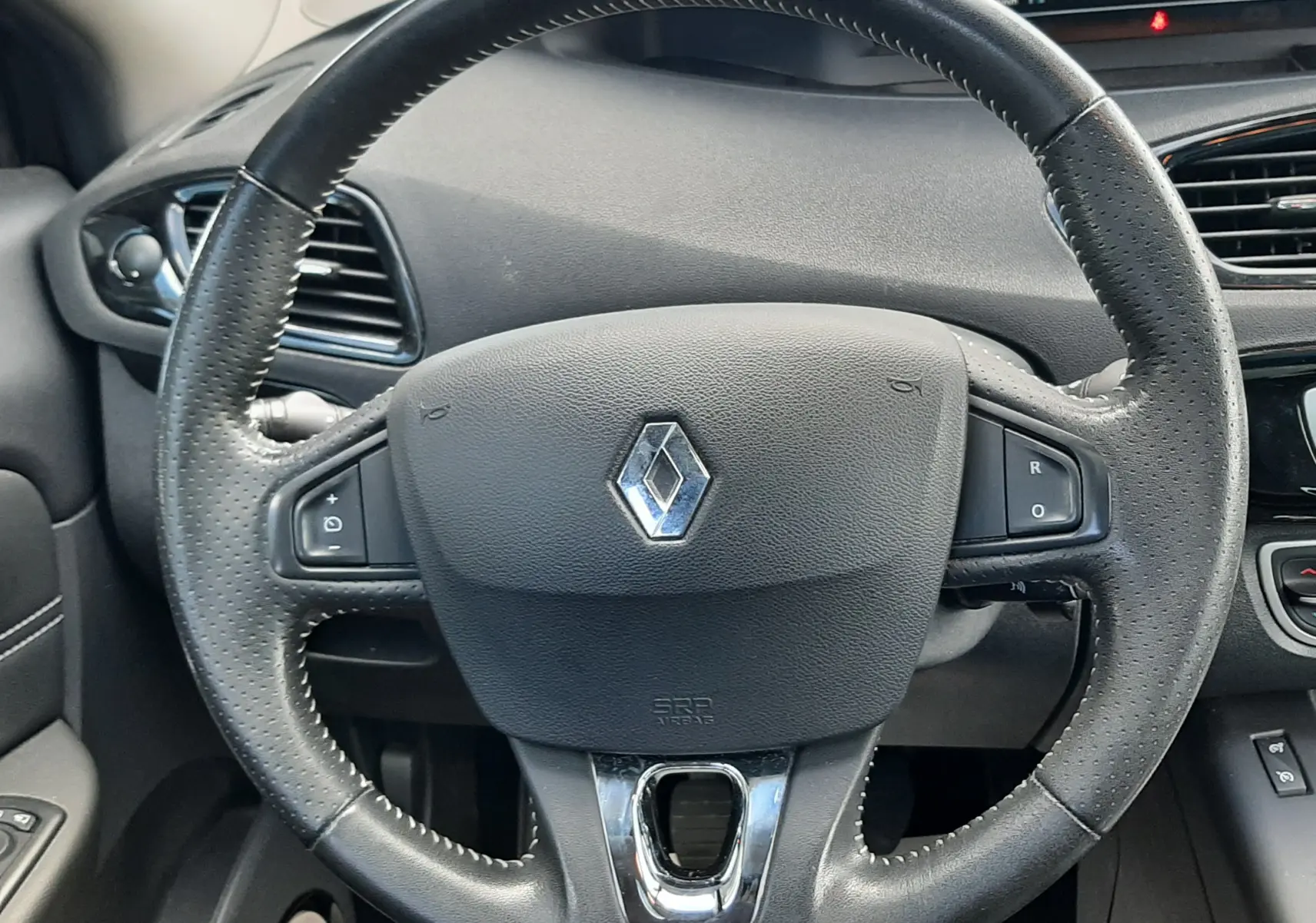 Vue rapprochée du volant en cuir noir du Renault Grand Scenic DCI 110 Bose 7 places, avec commandes intégrées.