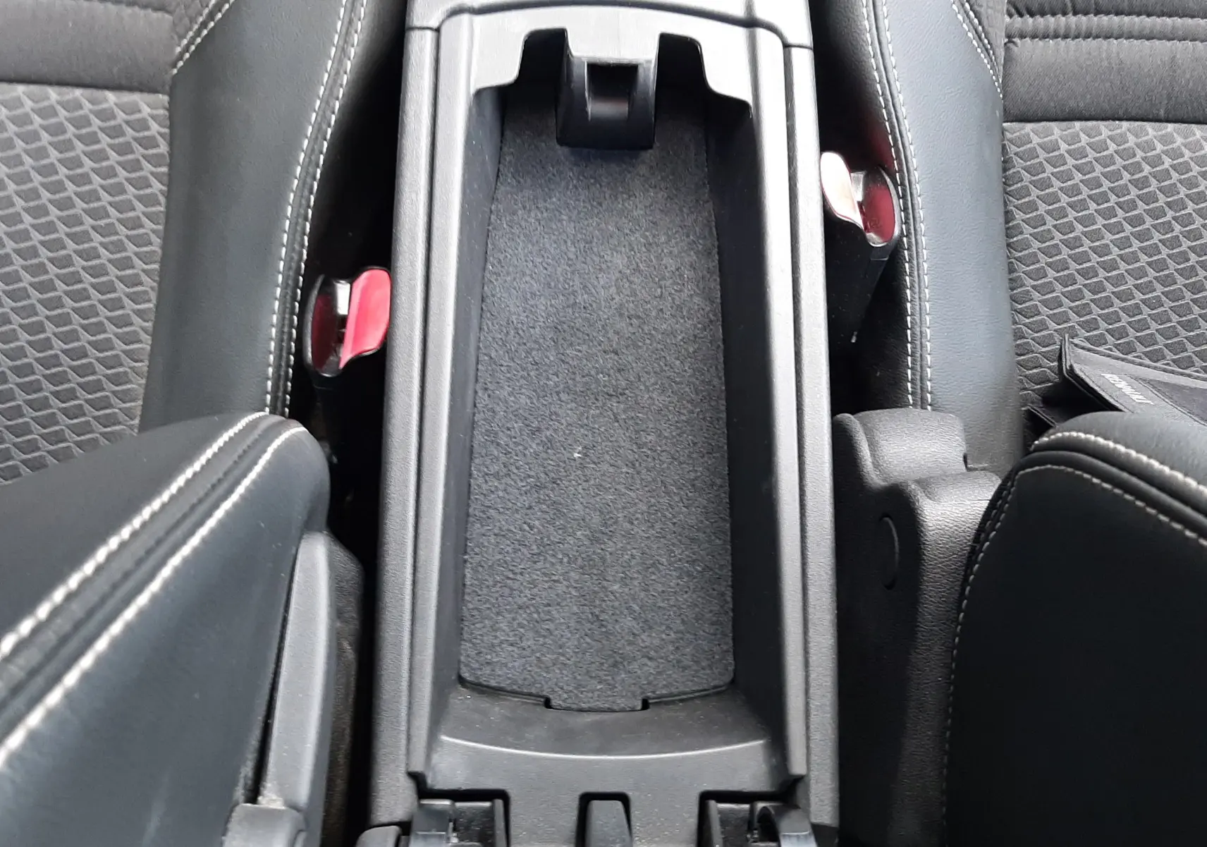 Vue plongeante sur la console centrale noire ouverte du Renault Grand Scenic DCI 110 Bose 7 places avec sièges en tissu et cuir.