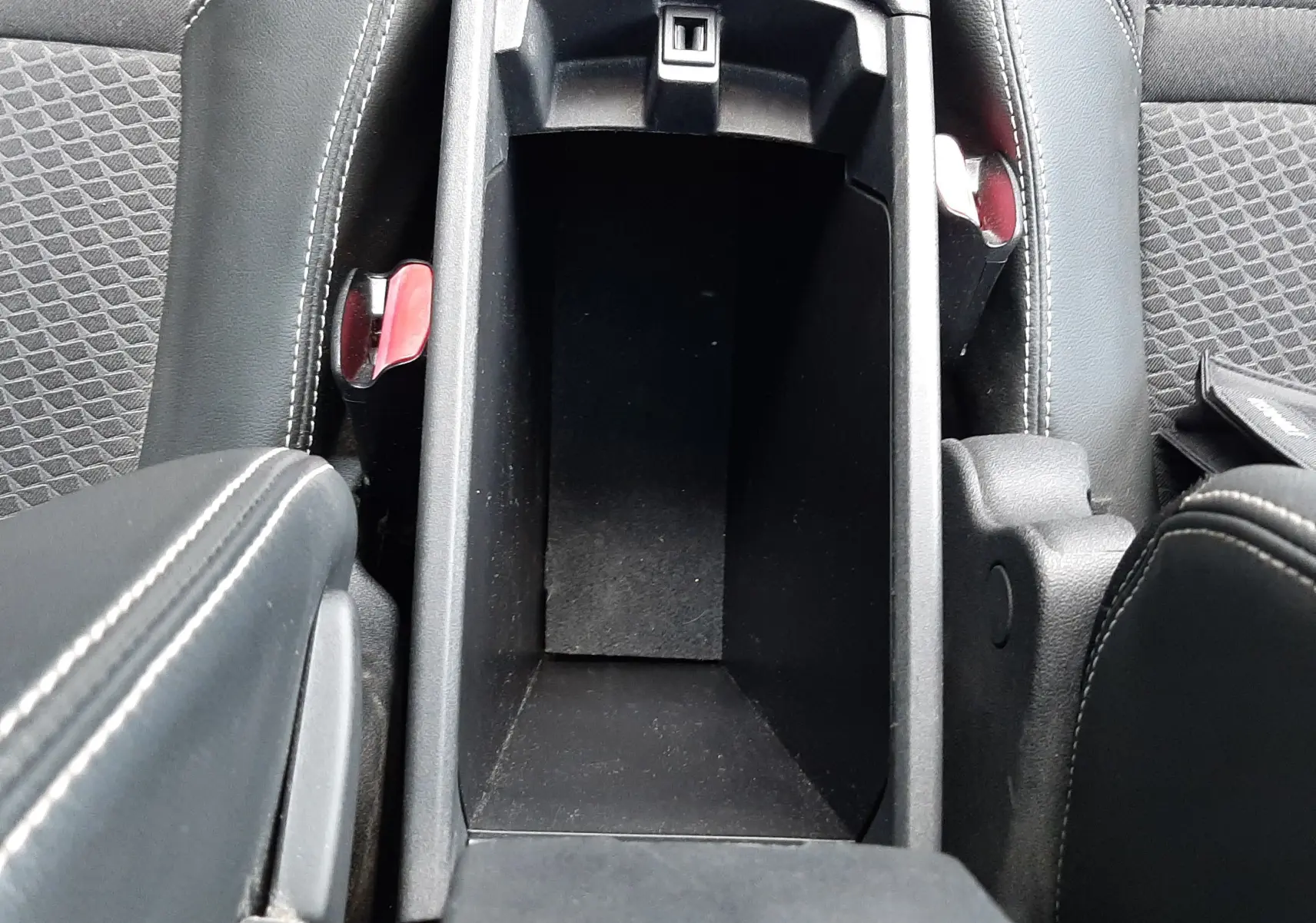 Vue plongeante sur le rangement central ouvert entre les sièges avant en tissu et cuir noir du Renault Grand Scenic DCI 110 Bose 7 places.