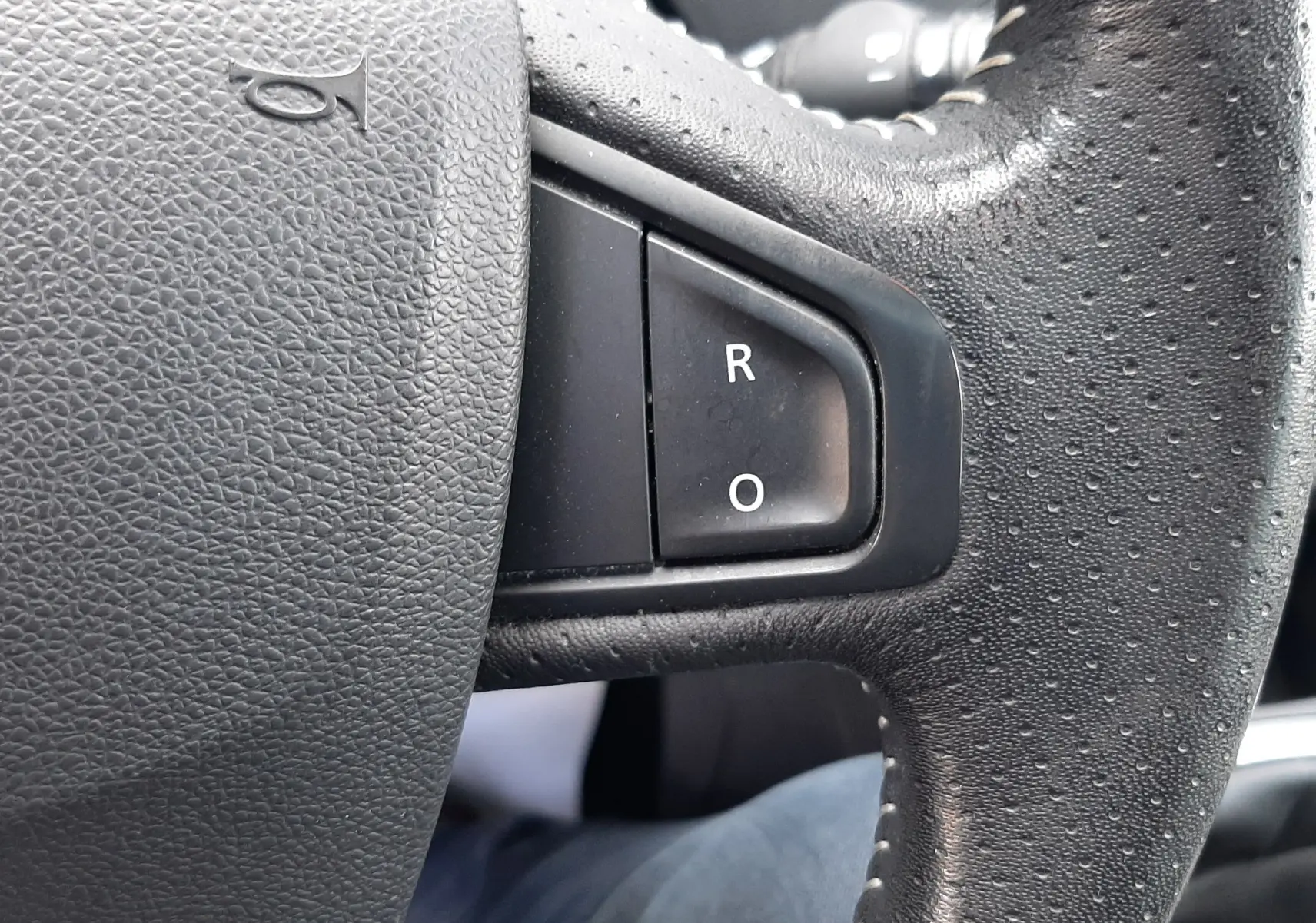 Gros plan sur le volant noir du Renault Grand Scenic 2015, mettant en valeur les boutons "R" et "O" sur la partie droite.