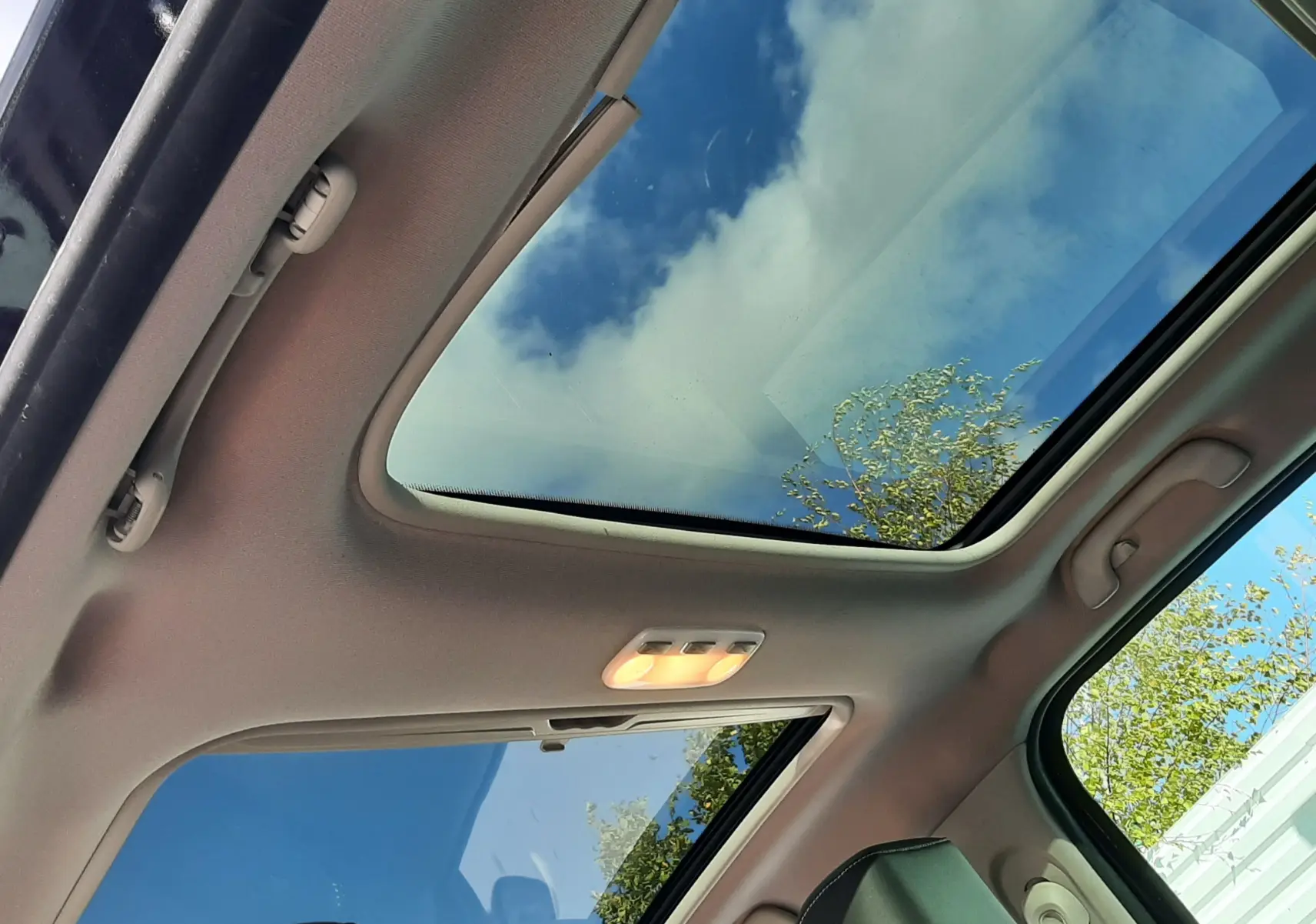 Toit panoramique ouvert montrant le ciel depuis l'intérieur noir du Renault Grand Scenic DCI 110 Bose 7 places de 2015.