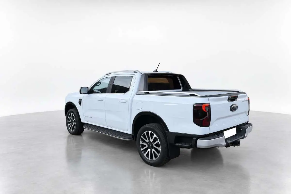Ford Ranger blanc glacier vu en 3/4 arrière droit, avec rideau de benne et jantes alu noires et argentées.