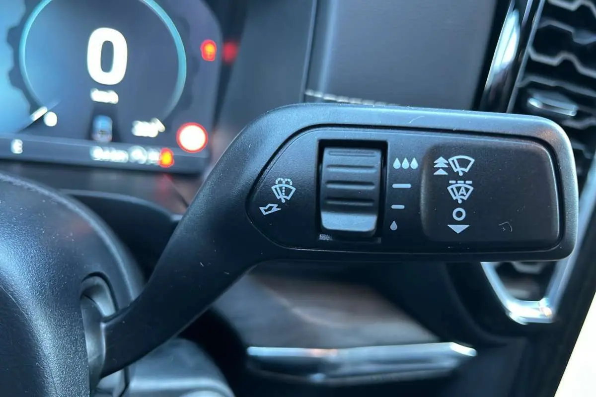 Gros plan sur la commande des essuie-glaces du Ford Ranger 2026, intérieur noir avec tableau de bord numérique flou.