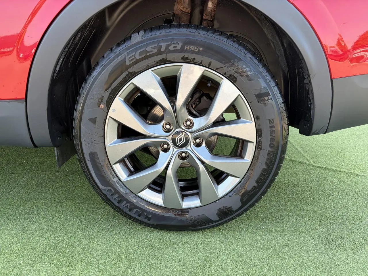 Gros plan sur la roue avant droite d’un Renault Arkana rouge flamme métal avec jante alliage grise 17 pouces Bahamas.