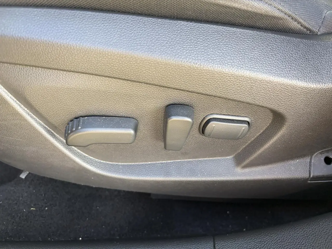 Gros plan sur les commandes de réglage électrique du siège conducteur du Renault Arkana 2025.