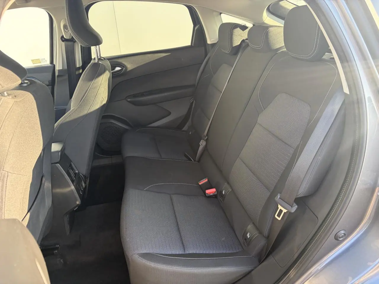 Vue intérieure côté droit sur la banquette arrière noire du Renault Arkana 2025, tissu avec surpiqûres contrastantes.