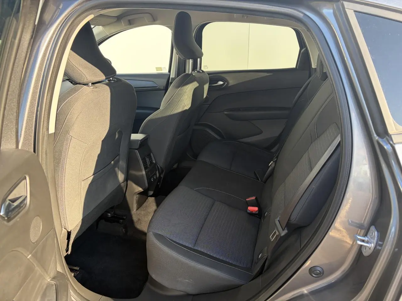 Vue intérieure arrière côté droit du Renault Arkana 2025, sièges tissu noirs et espace passagers visible.