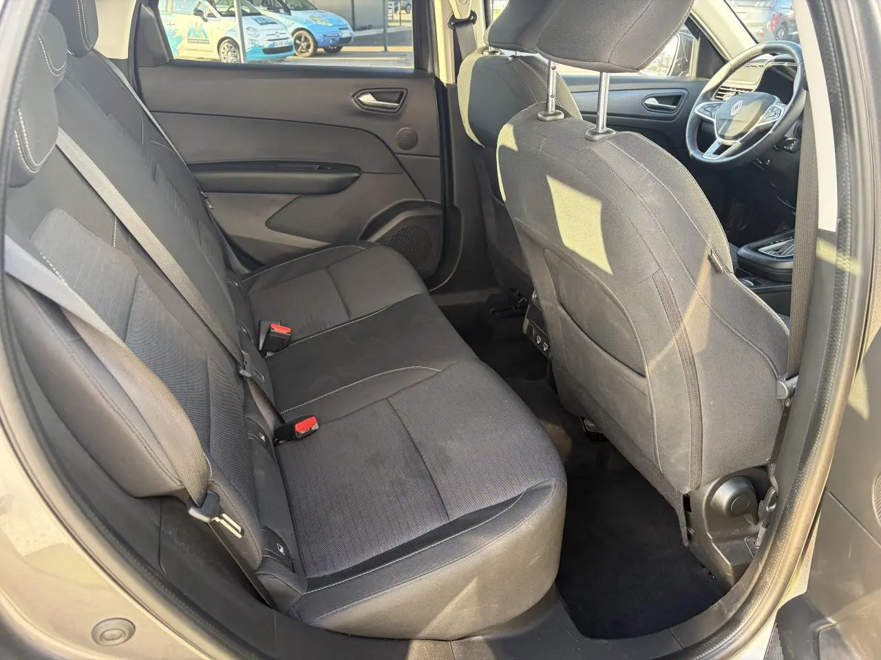 Vue intérieure arrière côté gauche montrant les sièges noirs et l'habitacle spacieux du Renault Arkana 2025.