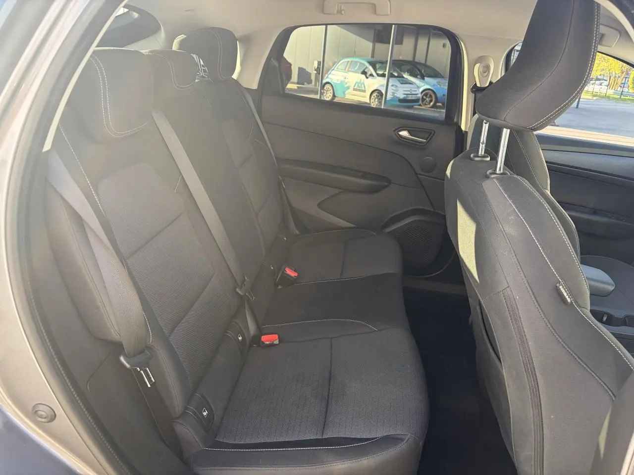 Vue intérieure arrière côté gauche de la Renault Arkana 2025, sièges tissu noirs avec surpiqûres blanches.