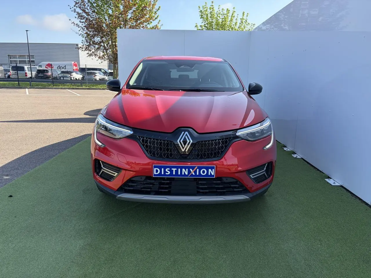 Vue de face du Renault Arkana 2025 rouge flamme métal avec calandre noire et logo Renault centré.