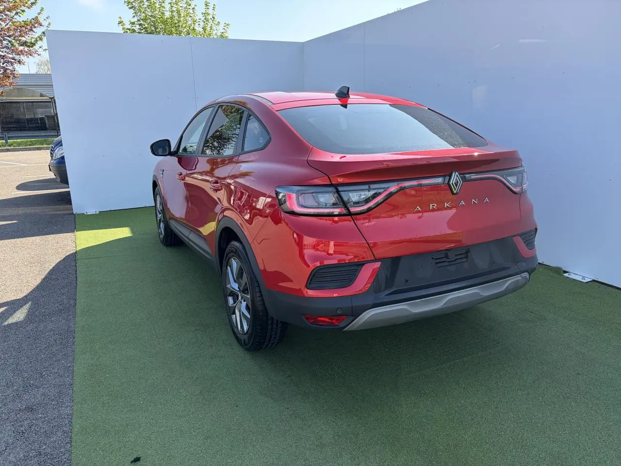 Vue 3/4 arrière droite d'un Renault Arkana rouge flamme métal, avec feux arrière LED et jantes alliage grises 17 pouces.