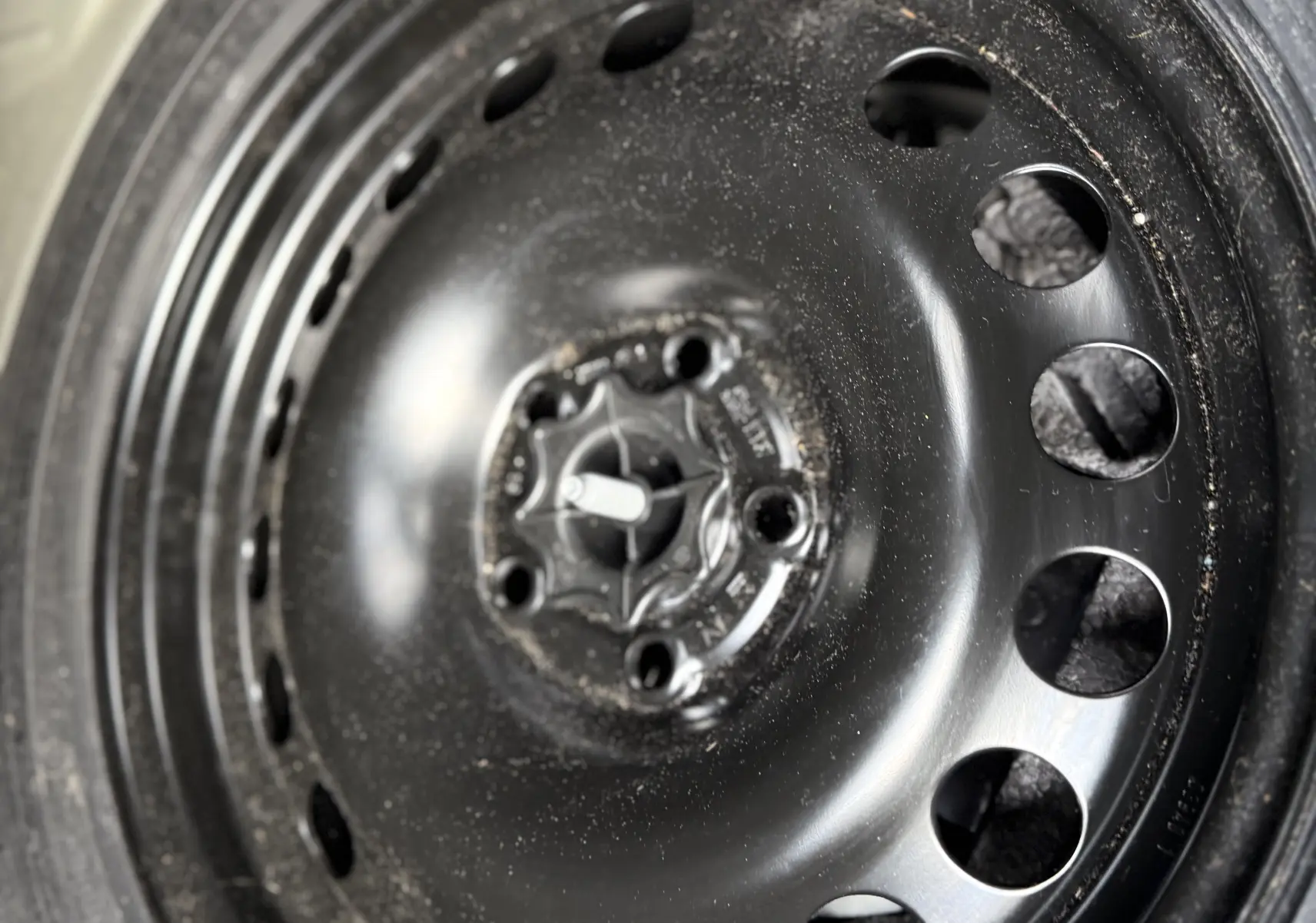 Gros plan sur la roue de secours noire en acier de l'Opel Astra gris 2010, montrant le pneu et la valve.