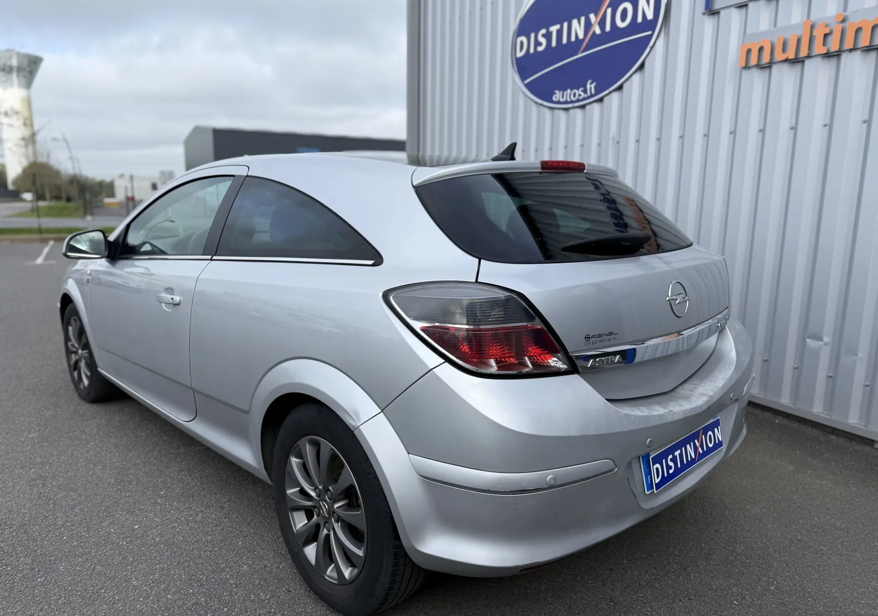 Vue 3/4 arrière droite d'une Opel Astra gris clair de 2010 avec hayon, jantes alliage et vitres teintées.