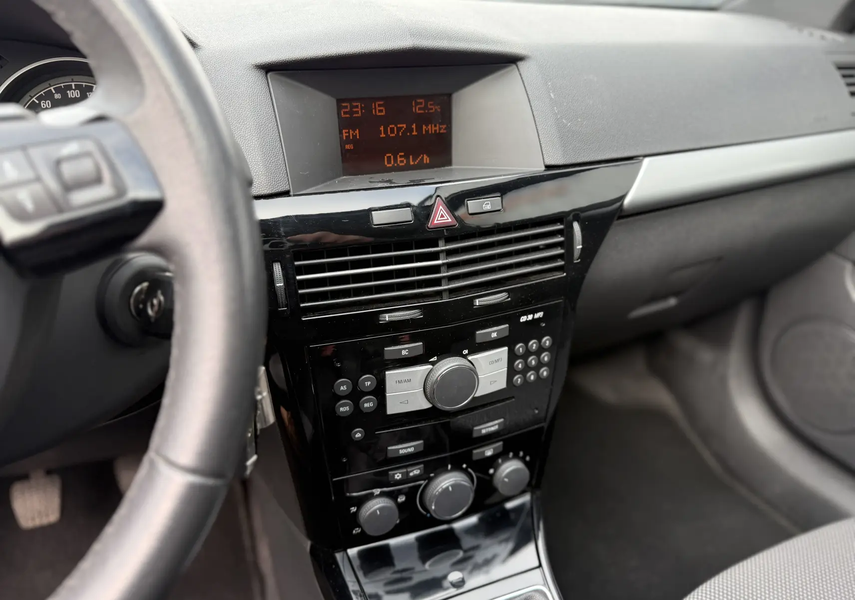 Intérieur de l’Opel Astra 1.7 CDTI 2010, vue centrale du tableau de bord avec console noire brillante et écran digital orange.