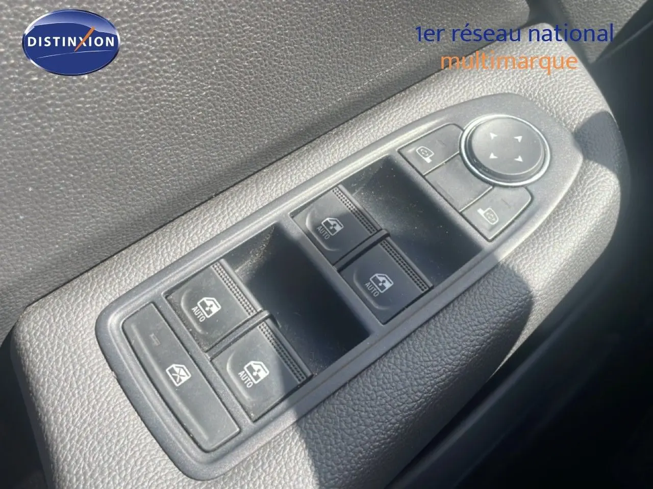 Gros plan sur les commandes des vitres électriques côté conducteur d'une Renault Clio blanche, intérieur noir.