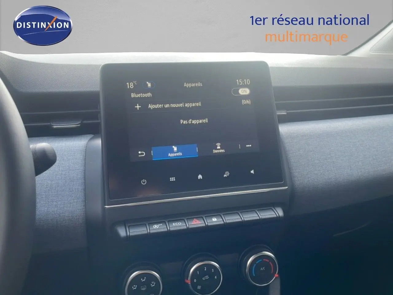 Vue intérieure centrée sur l’écran tactile et la console de la Renault Clio blanche, avec détails des commandes climatisation.