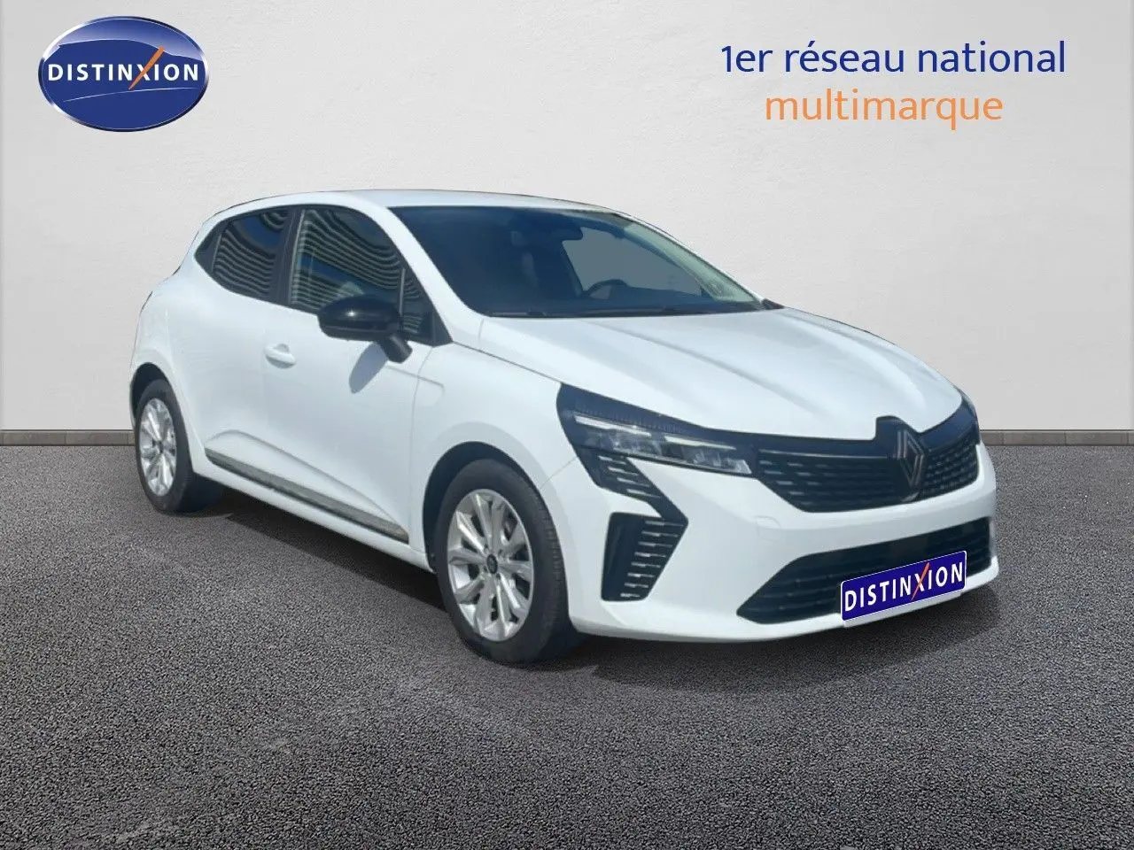 Renault Clio blanche vue 3/4 avant droit, avec calandre noire et jantes alliage 16 pouces visibles.