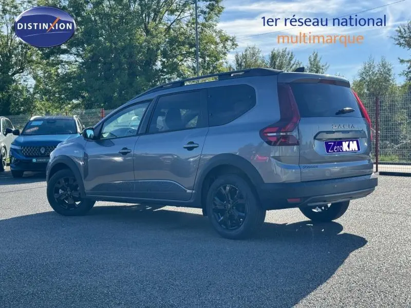 Vue 3/4 arrière droite du Dacia Jogger gris schiste métallisé avec barres de toit et jantes noires.