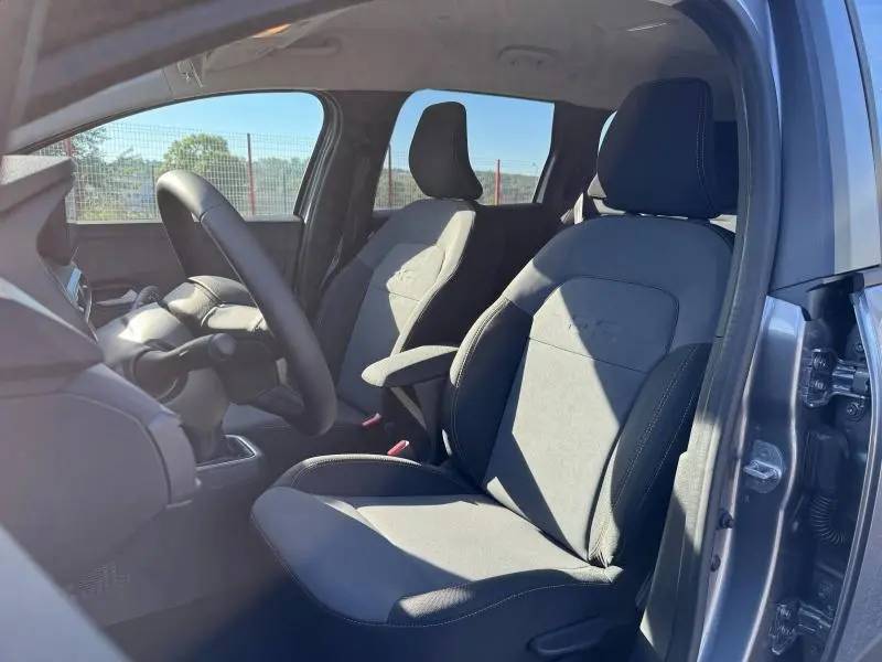 Vue intérieure côté gauche du poste de conduite du Dacia Jogger gris Schiste, avec sièges tissu et volant visible.